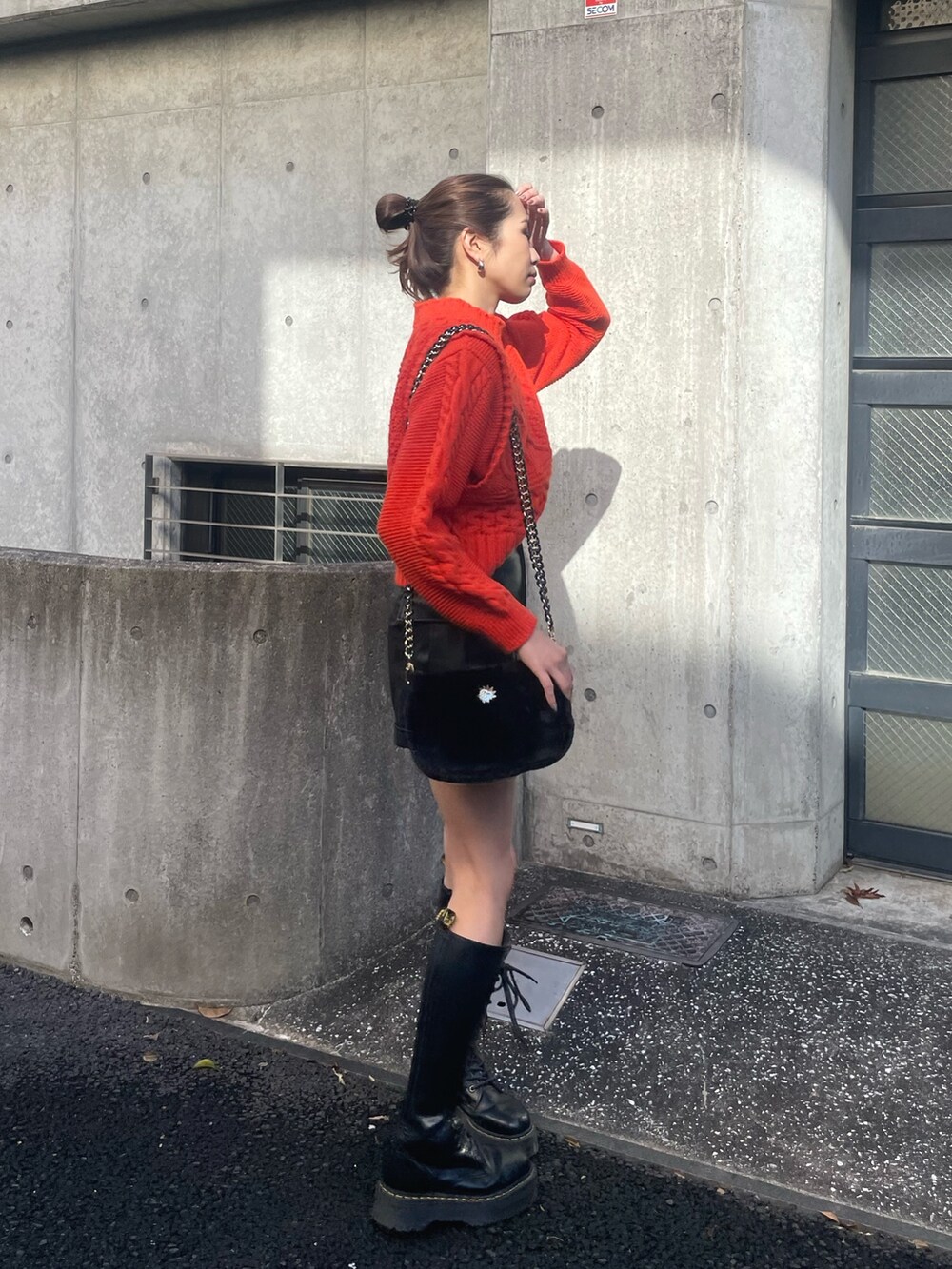 オレンジ系のニット/セーター、ブラック系のその他パンツ、ブラック系のショルダーバッグを着用したレディースの冬コーディネートの6枚目の写真