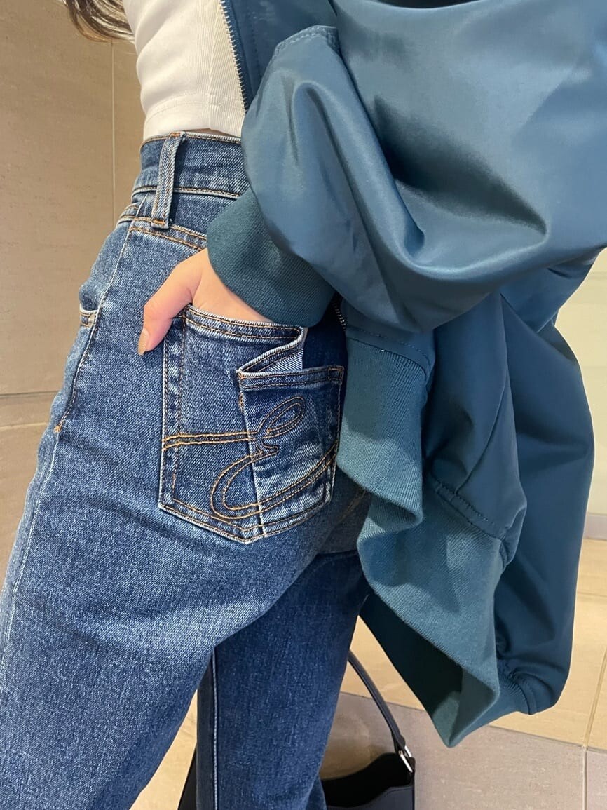 ブルー系のMA-1、ブラック系のブーツ、ブルー系のデニムパンツを着用したレディースの秋コーディネートの5枚目の写真