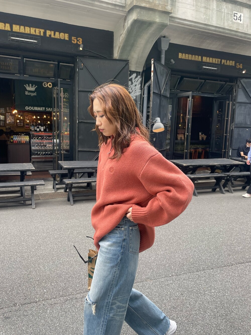 オレンジ系のニット/セーター、ブルー系のデニムパンツを着用したレディースの夏コーディネートの6枚目の写真