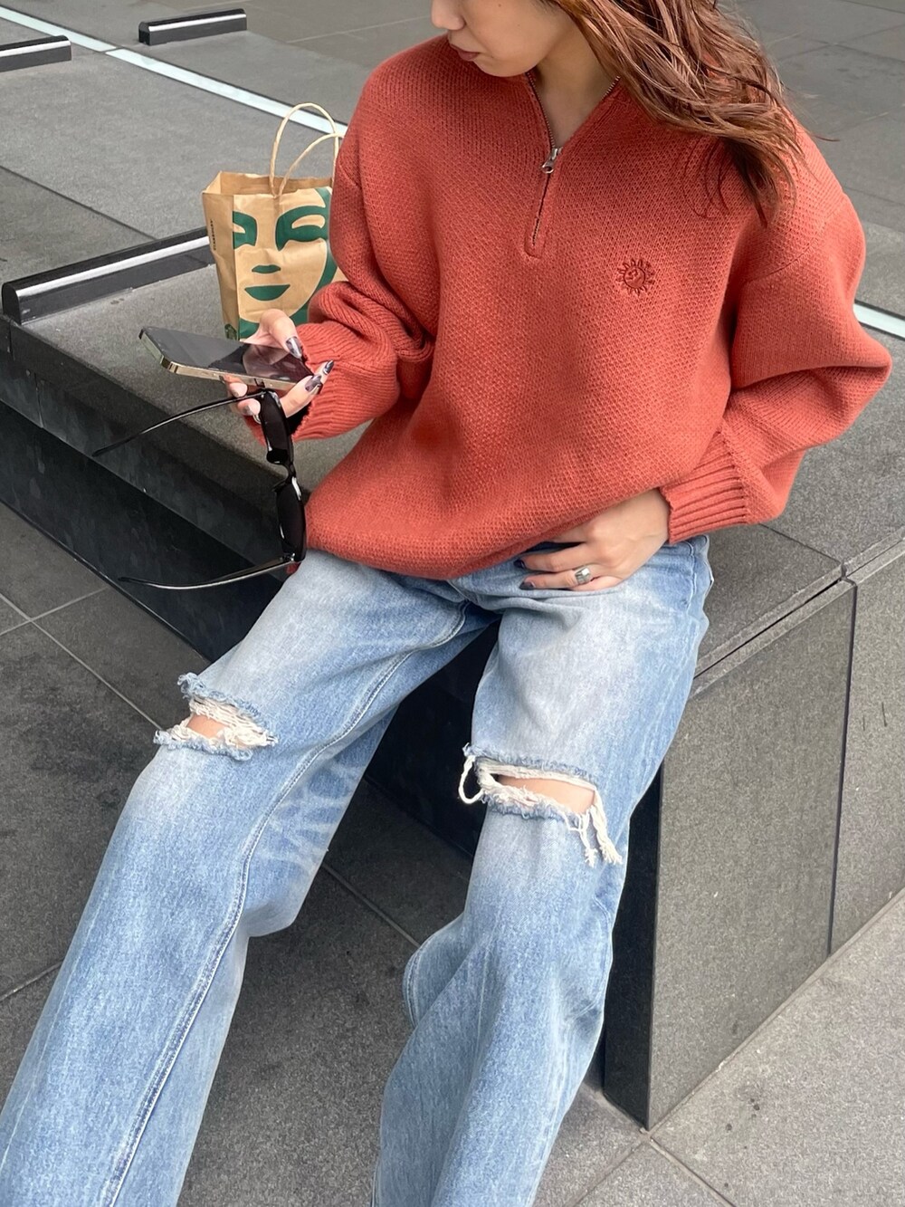 オレンジ系のニット/セーター、ブルー系のデニムパンツを着用したレディースの夏コーディネートの3枚目の写真