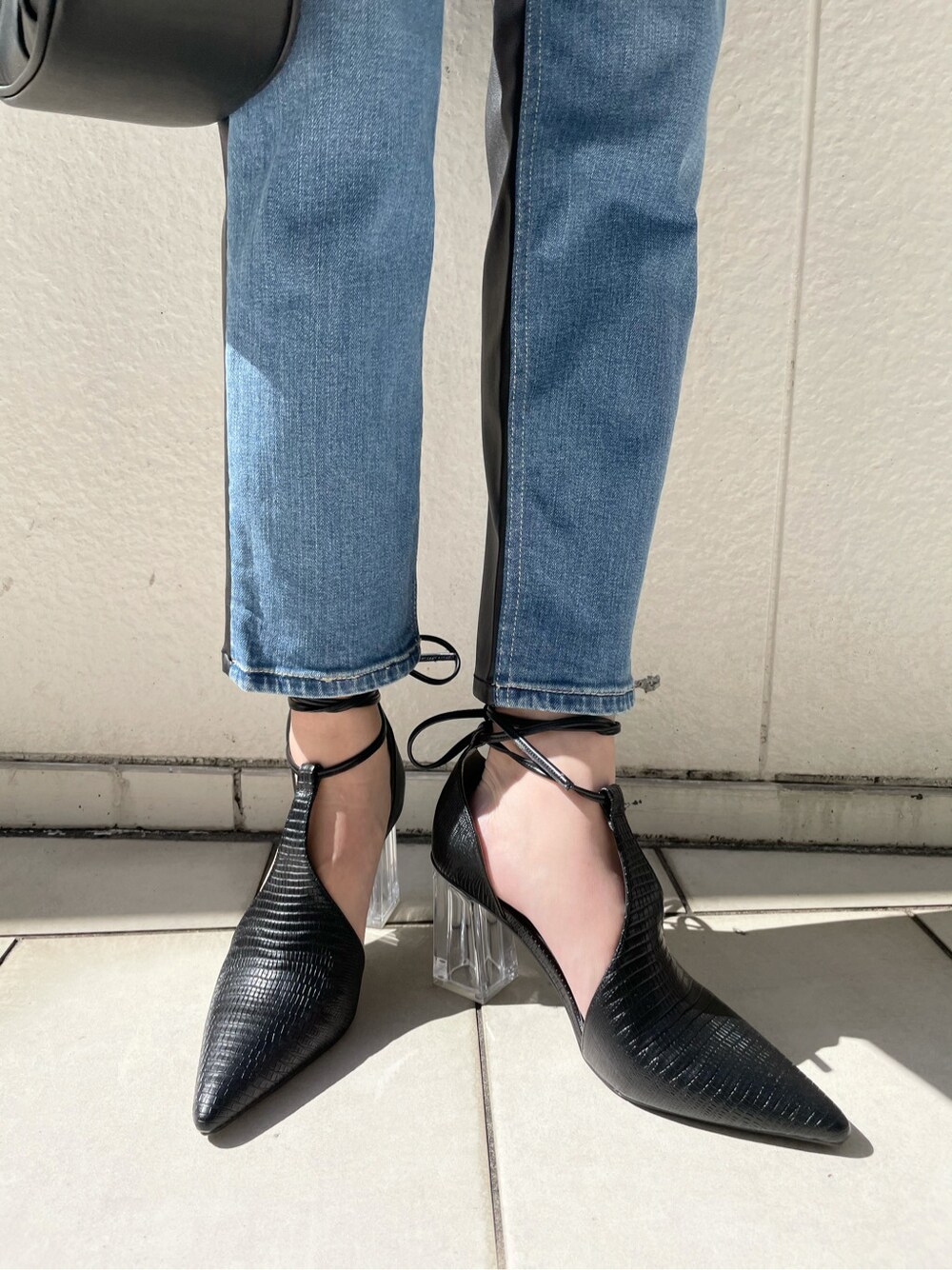 ブラック系のパンプス、ブルー系のデニムパンツ、ブラック系のハンドバッグを着用したレディースの春コーディネートの7枚目の写真