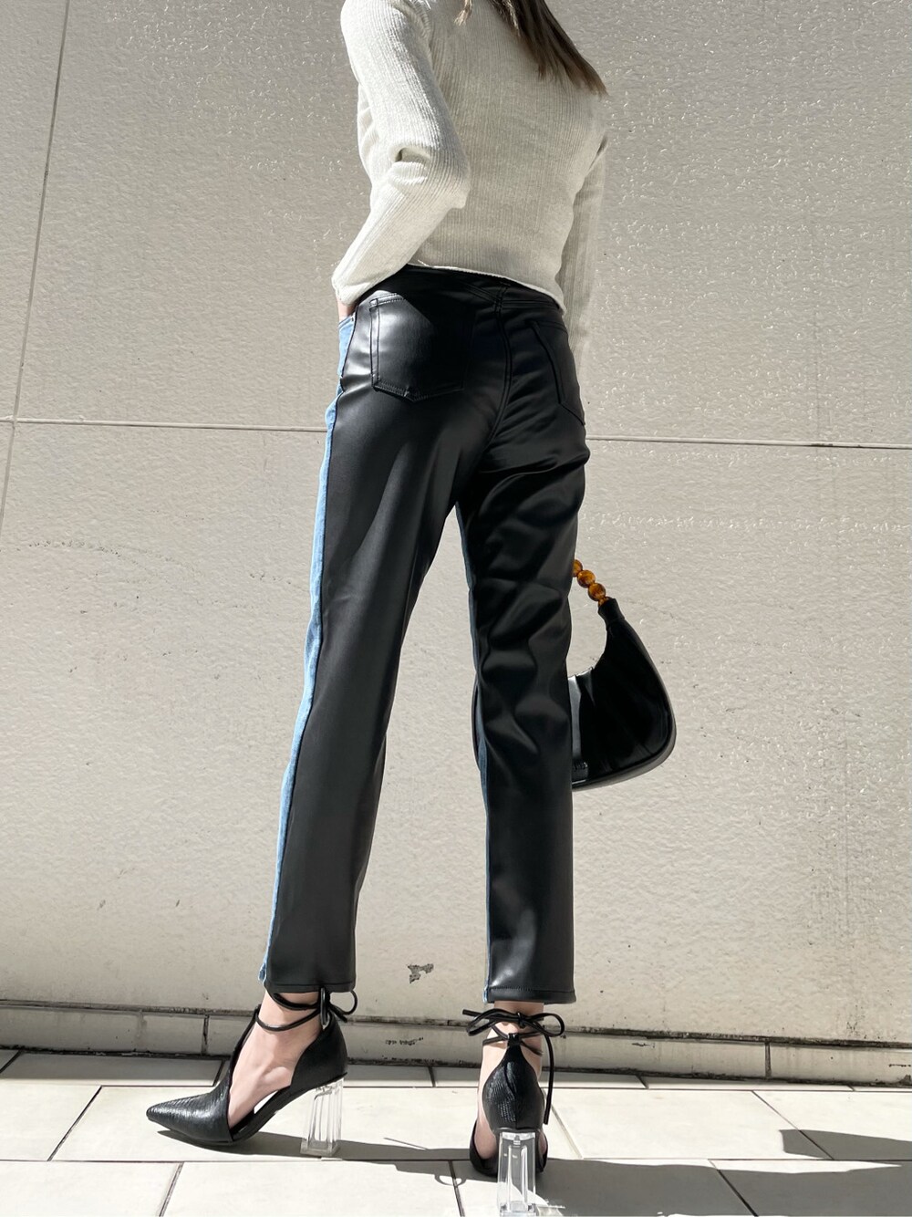 ブラック系のパンプス、ブルー系のデニムパンツ、ブラック系のハンドバッグを着用したレディースの春コーディネートの5枚目の写真