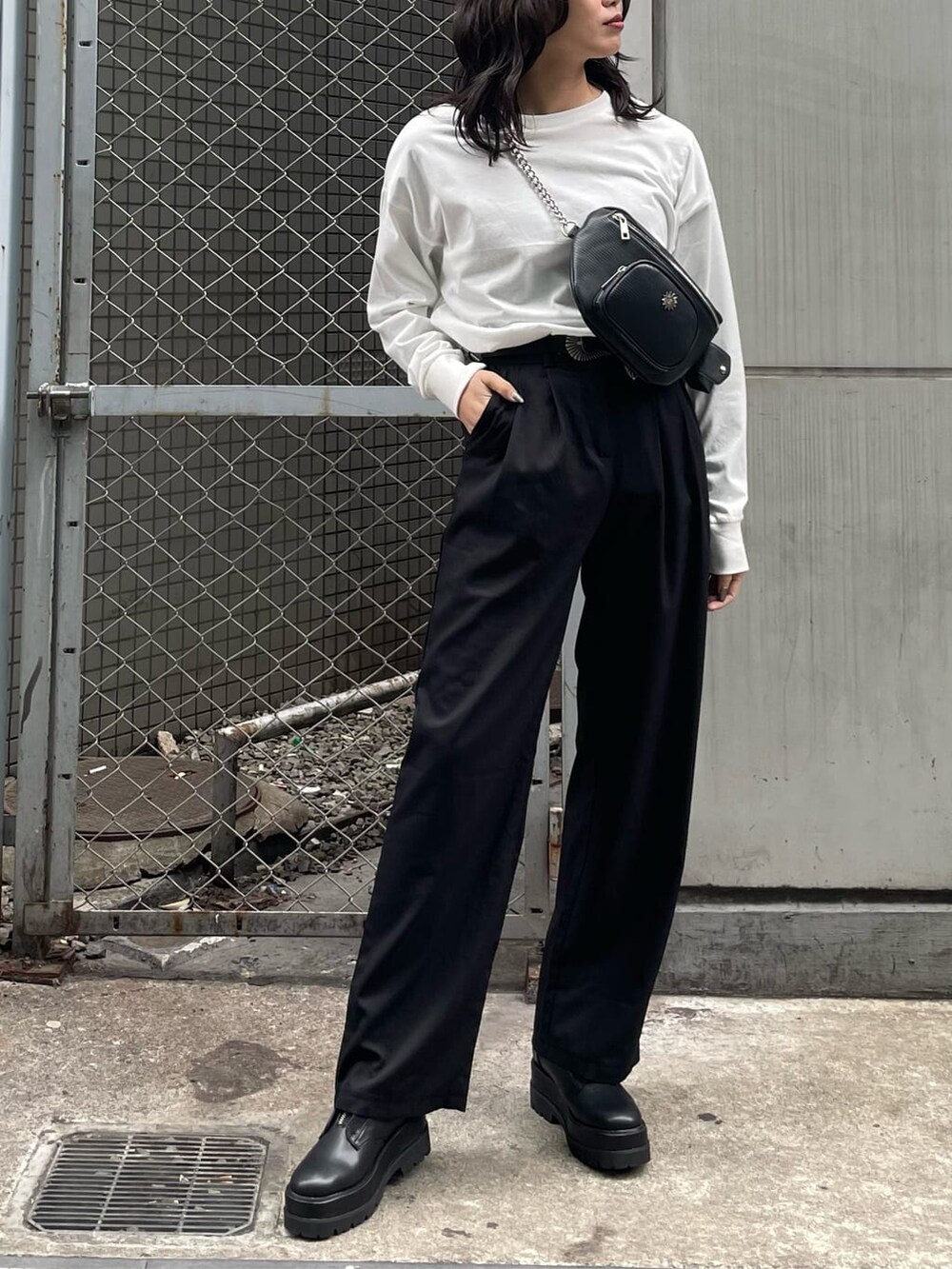 ブラック系のボディバッグ/ウエストポーチ、ブラック系のブーツ、ホワイト系のTシャツ/カットソーを着用したレディースの冬コーディネートの2枚目の写真