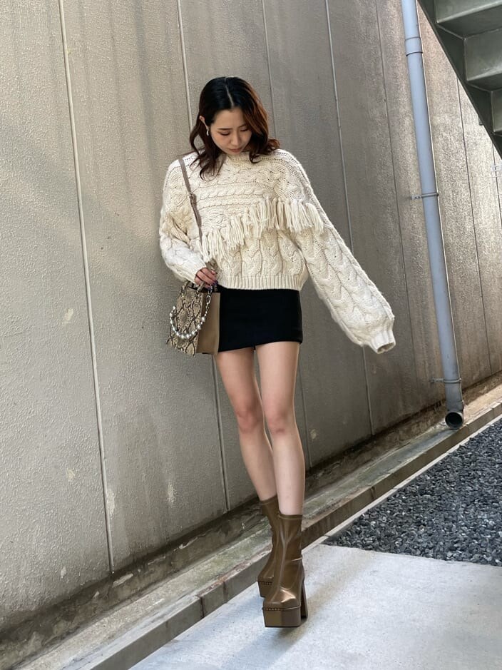 ベージュ系のブーツ、ホワイト系のニット/セーター、ブラック系のスカートを着用したレディースの秋コーディネートの2枚目の写真