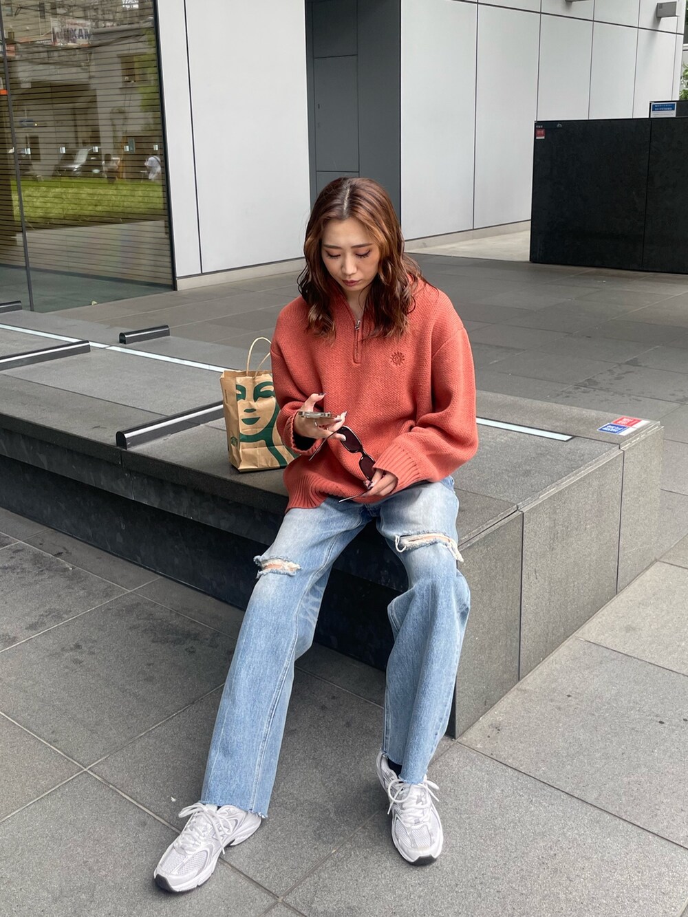 オレンジ系のニット/セーター、ブルー系のデニムパンツを着用したレディースの夏コーディネートの5枚目の写真