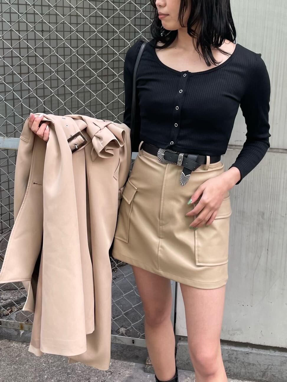 ベージュ系のスカート、ブラック系のブーツ、ベージュ系のトレンチコートを着用したレディースの春コーディネートの5枚目の写真