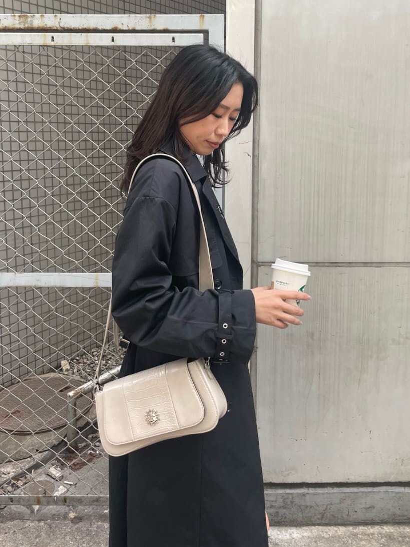 ブラック系のブーツ、ブラック系のトレンチコート、ブラック系のワンピースを着用したレディースの春コーディネートの6枚目の写真