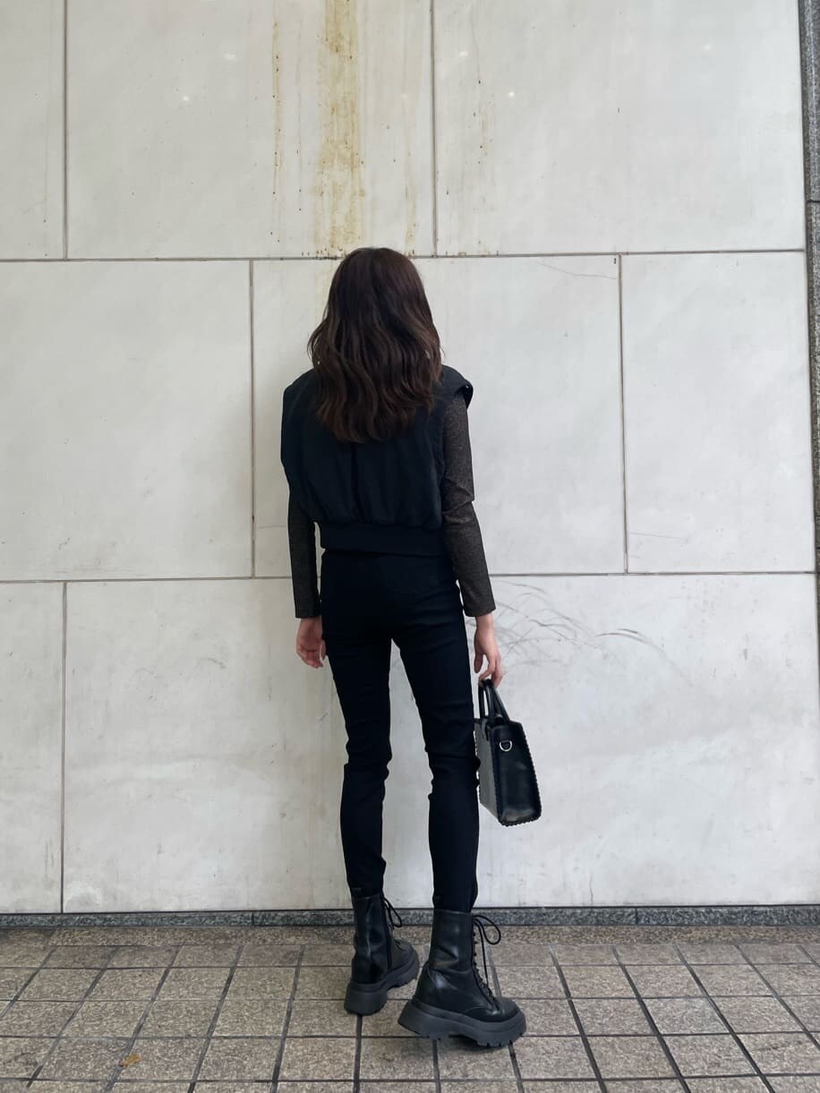 ブラック系のブーツ、ブラック系のデニムパンツ、ブラック系のショルダーバッグを着用したレディースの秋コーディネートの2枚目の写真