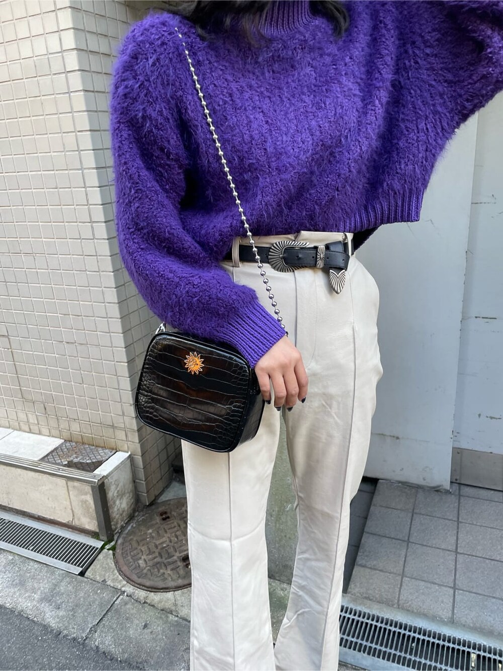 ブラック系のブーツ、パープル系のニット/セーター、ブラック系のショルダーバッグを着用したレディースの冬コーディネートの4枚目の写真