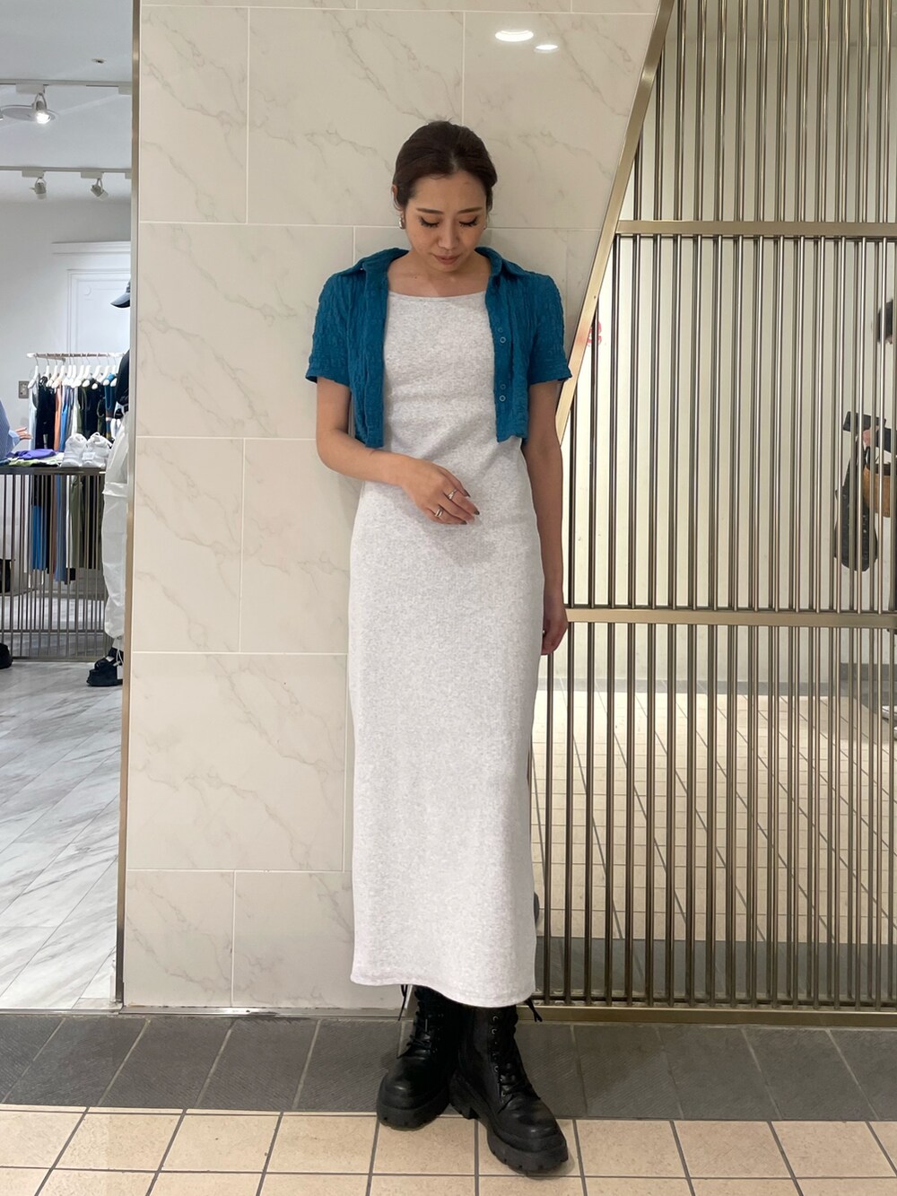 グレー系のワンピース、ブラック系のブーツ、ブルー系のシャツ/ブラウスを着用したレディースの春コーディネートの3枚目の写真