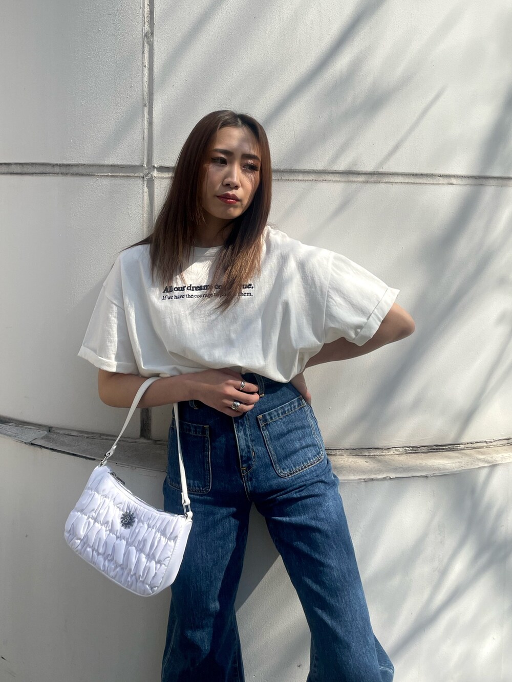 ホワイト系のTシャツ/カットソー、ブルー系のデニムパンツ、ホワイト系のハンドバッグを着用したレディースの春コーディネートの3枚目の写真