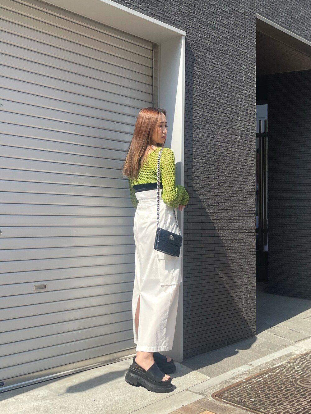 グリーン系のニット/セーター、ブラック系のニット/セーター、ホワイト系のスカートを着用したレディースの春コーディネートの2枚目の写真