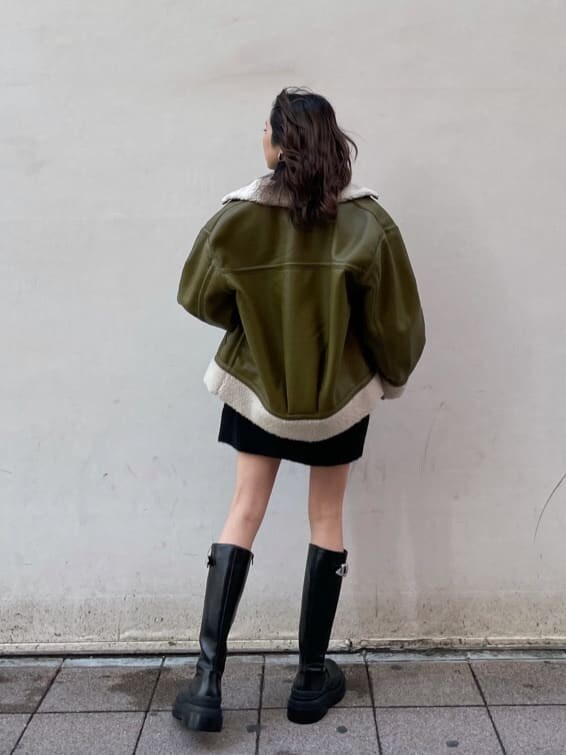 グリーン系のブルゾン、ブラック系のショルダーバッグ、ブラック系のワンピースを着用したレディースの冬コーディネートの8枚目の写真