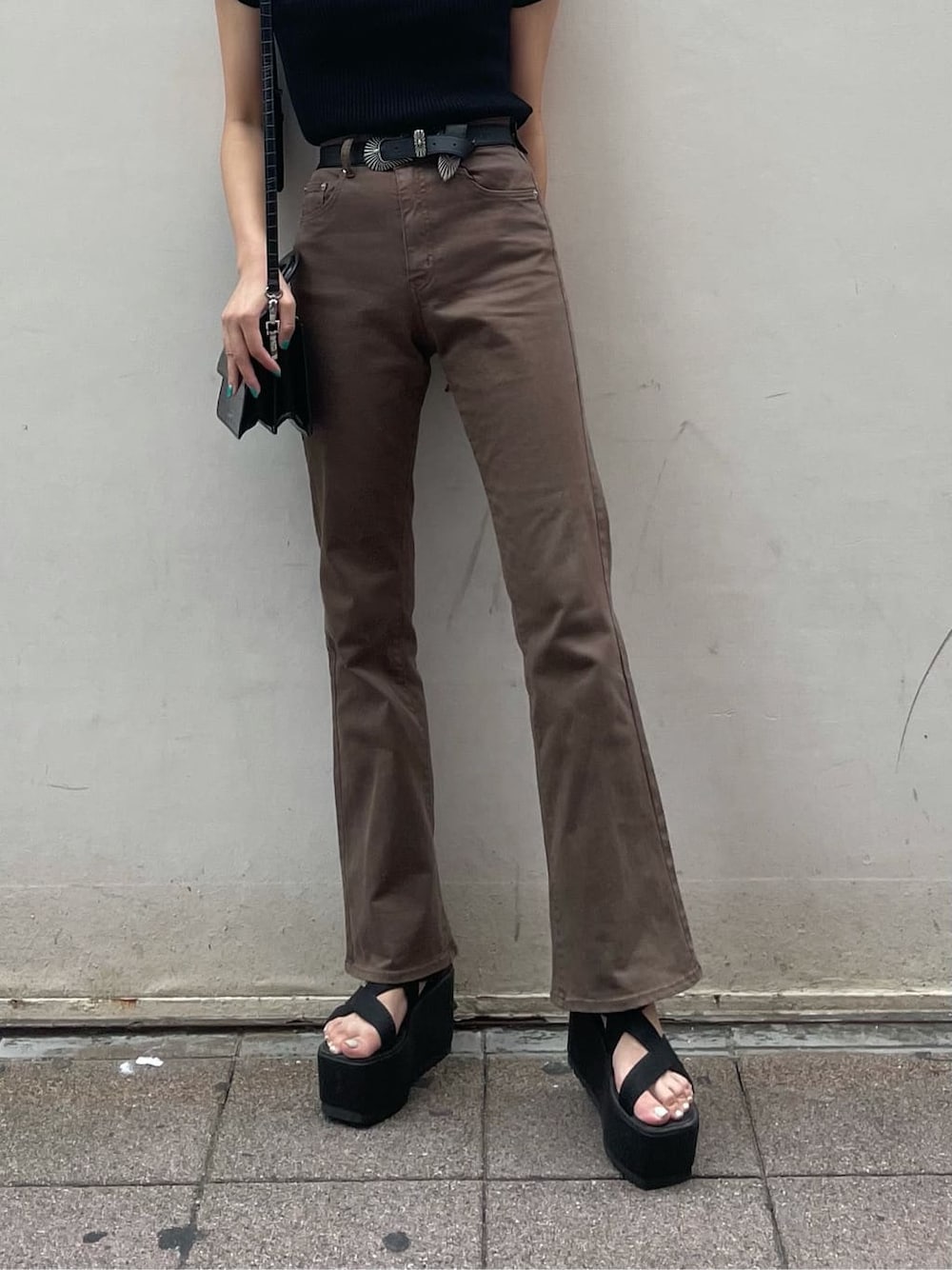 ブラウン系のデニムパンツ、ブラック系のサンダル、ブラック系のニット/セーターを着用したレディースの秋コーディネートの5枚目の写真