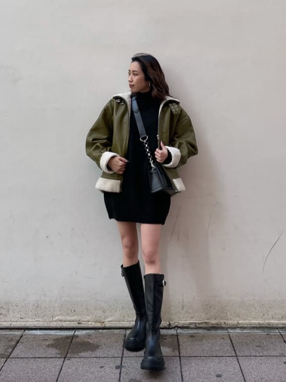 グリーン系のブルゾン、ブラック系のショルダーバッグ、ブラック系のワンピースを着用したレディースの冬コーディネートの7枚目の写真