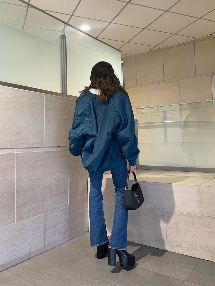 ブルー系のMA-1、ブラック系のブーツ、ブルー系のデニムパンツを着用したレディースの秋コーディネートの2枚目の写真