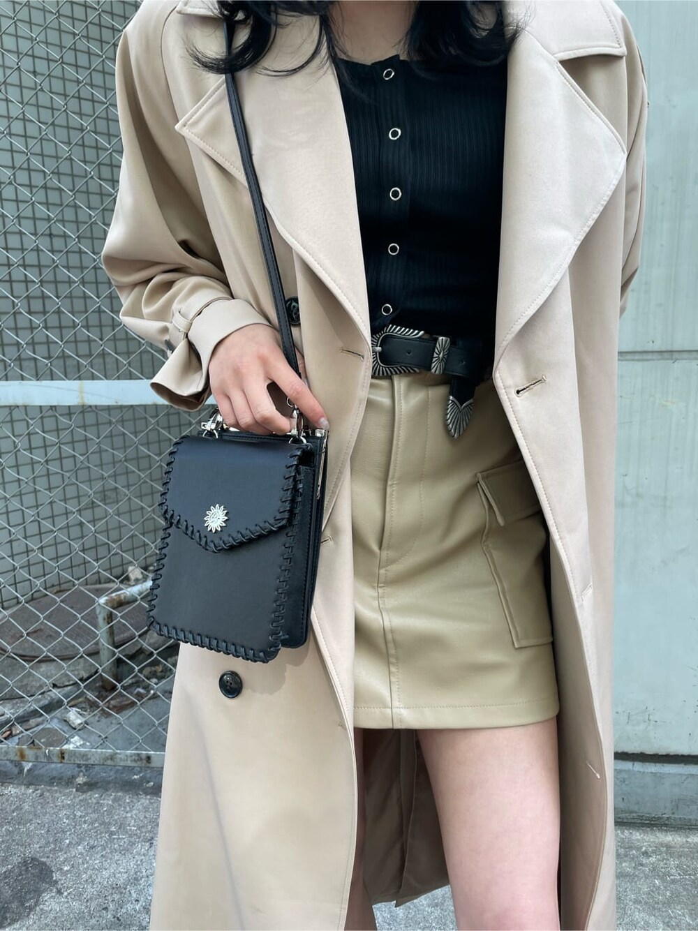 ブラック系のブーツ、ベージュ系のトレンチコート、ブラック系のショルダーバッグを着用したレディースの春コーディネートの7枚目の写真