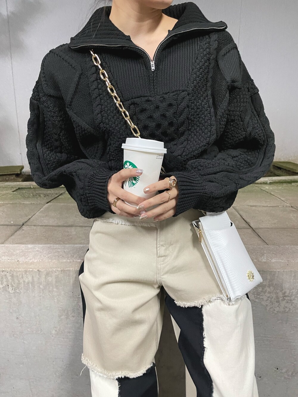 ブラック系のブーツ、ホワイト系のショルダーバッグ、ブラック系のニット/セーターを着用したレディースの冬コーディネートの6枚目の写真