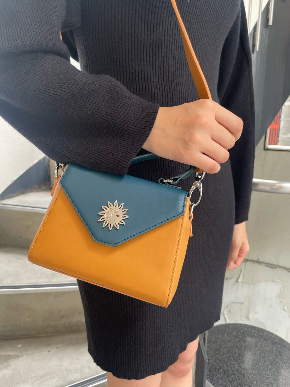 ブラック系のワンピース、ブラック系のブーツ、イエロー系のショルダーバッグを着用したレディースの秋コーディネートの7枚目の写真