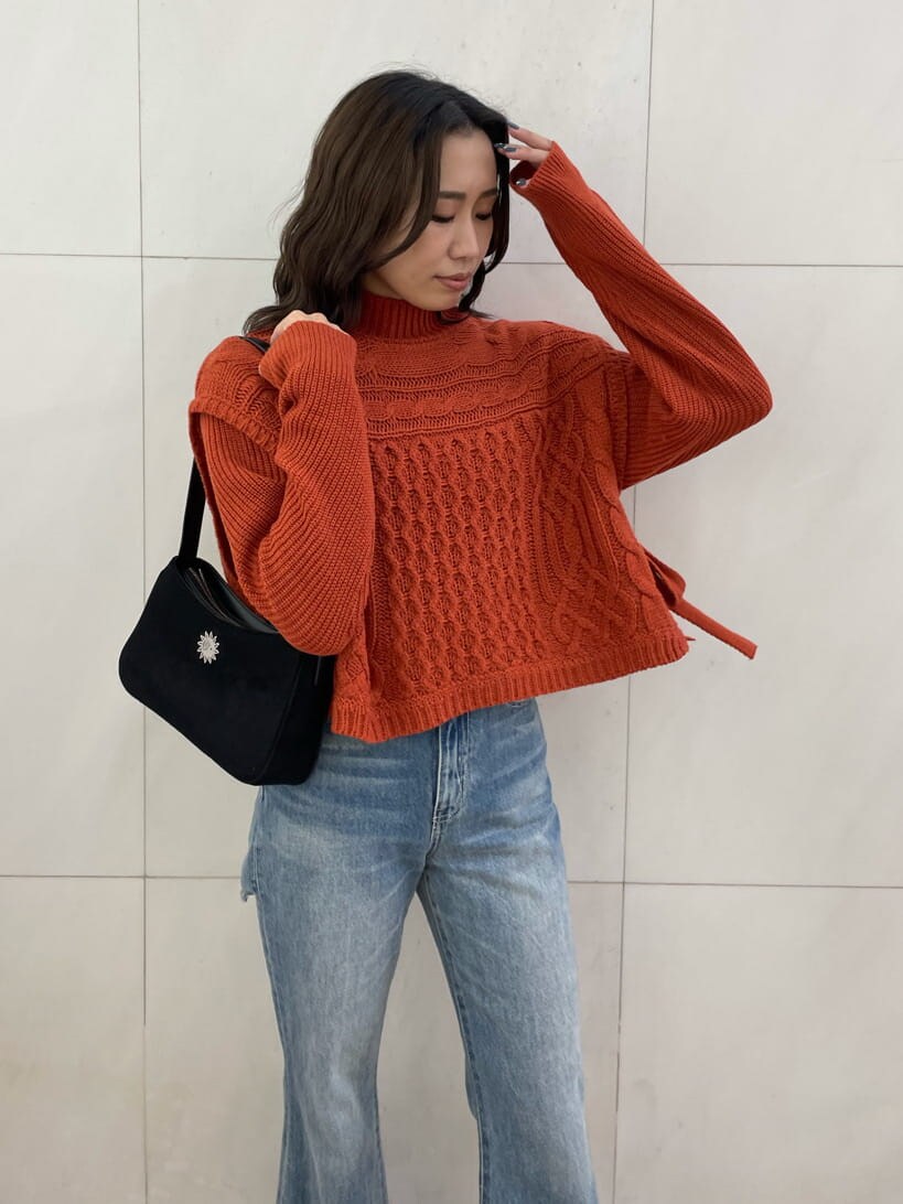 ブルー系のデニムパンツ、ブラック系のショルダーバッグ、オレンジ系のニット/セーターを着用したレディースの秋コーディネートの3枚目の写真