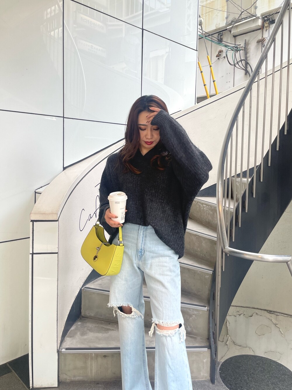グレー系のニット/セーター、イエロー系のハンドバッグ、ブルー系のデニムパンツを着用したレディースの秋コーディネートの4枚目の写真