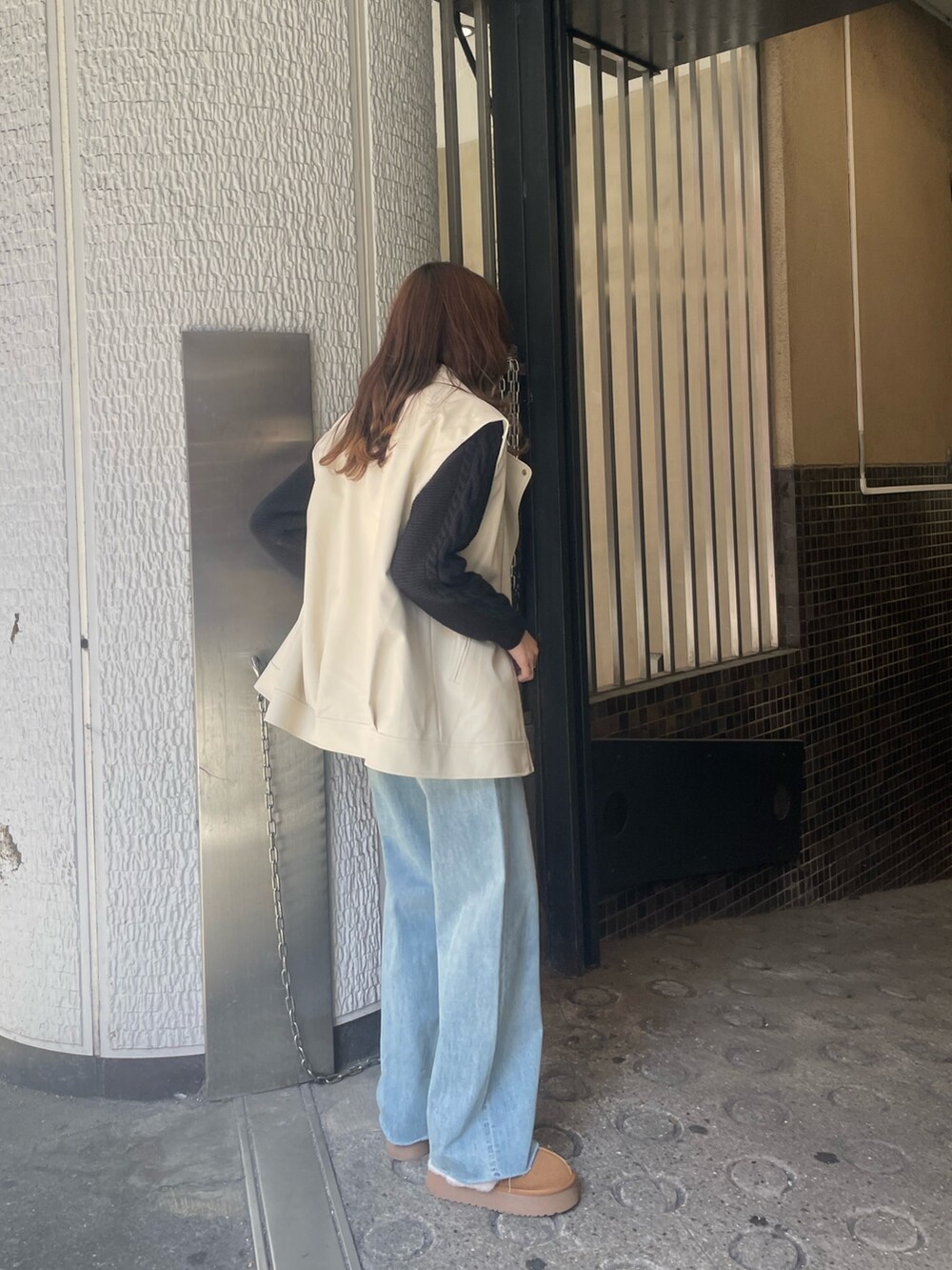 ブルー系のデニムパンツ、ブラック系のニット/セーター、ホワイト系のライダースジャケットを着用したレディースの冬コーディネートの3枚目の写真