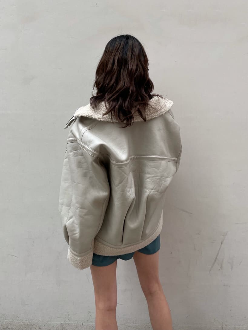 ホワイト系のブルゾン、ブルー系のスカート、ブラック系のTシャツ/カットソーを着用したレディースの冬コーディネートの7枚目の写真