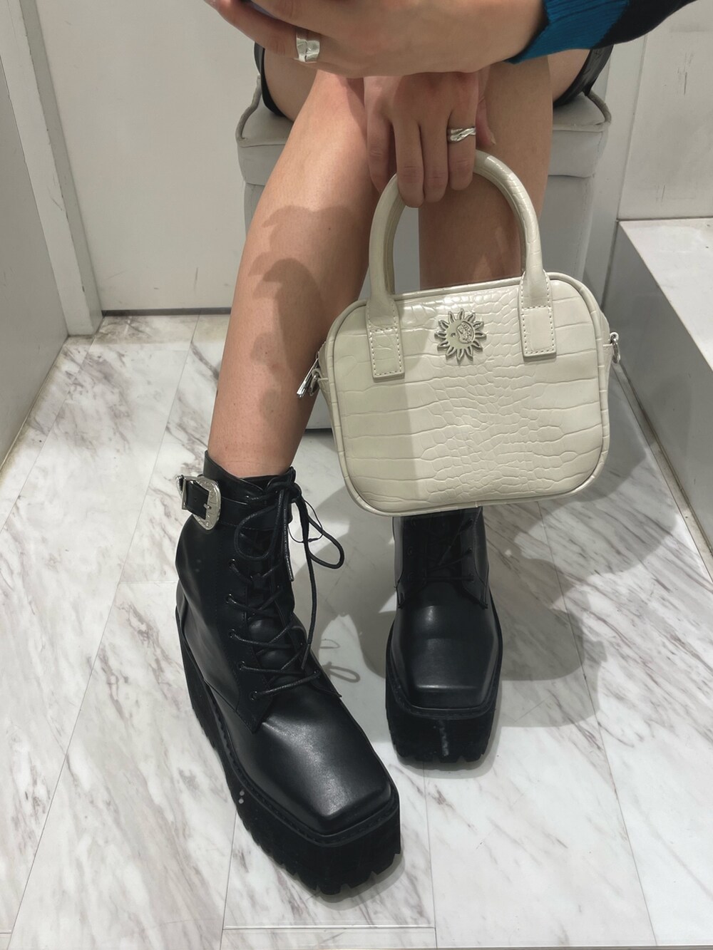 ブルー系のニット/セーター、ブラック系のスカート、ホワイト系のショルダーバッグを着用したレディースの冬コーディネートの4枚目の写真