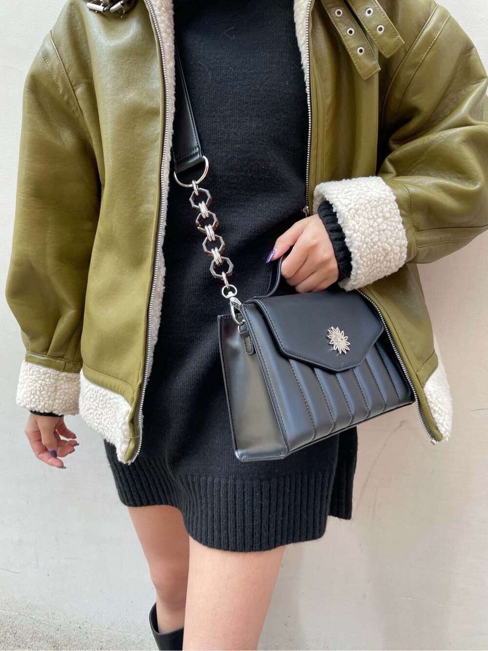 グリーン系のブルゾン、ブラック系のショルダーバッグ、ブラック系のワンピースを着用したレディースの冬コーディネートの4枚目の写真