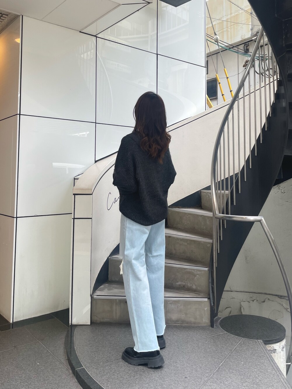 グレー系のニット/セーター、イエロー系のハンドバッグ、ブルー系のデニムパンツを着用したレディースの秋コーディネートの2枚目の写真