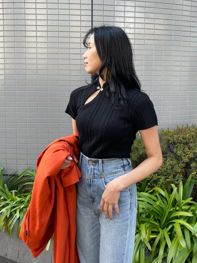 ブラック系のブーツ、オレンジ系のトレンチコート、ブルー系のデニムパンツを着用したレディースの春コーディネートの4枚目の写真