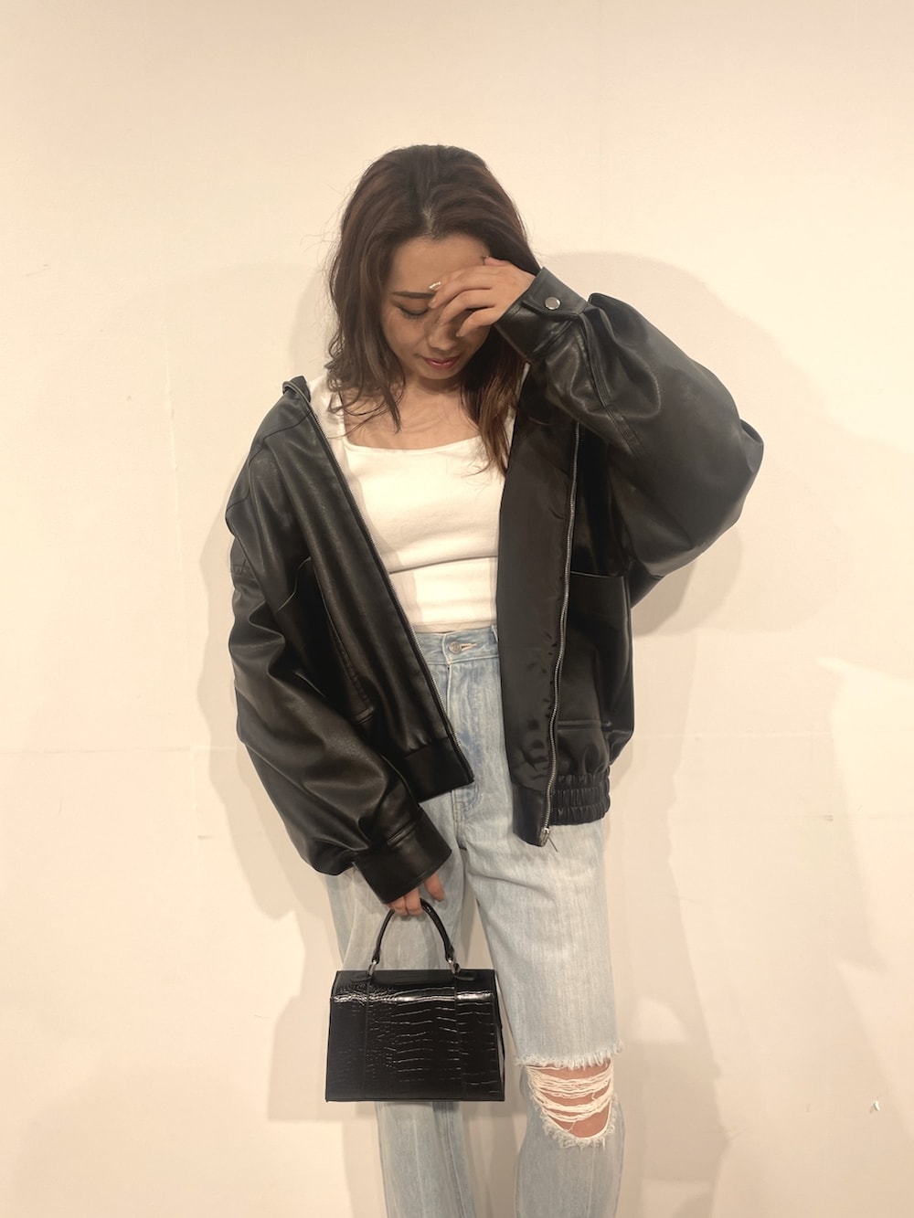 ブルー系のデニムパンツ、ブラック系のショルダーバッグ、ホワイト系のTシャツ/カットソーを着用したレディースの秋コーディネートの3枚目の写真