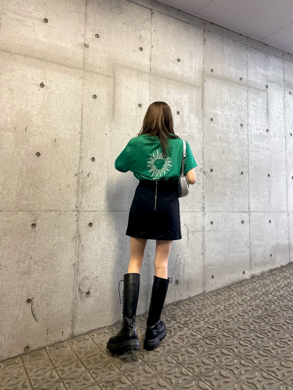 グリーン系のTシャツ/カットソー、ブラック系のスカート、ブラック系のブーツを着用したレディースの夏コーディネートの3枚目の写真