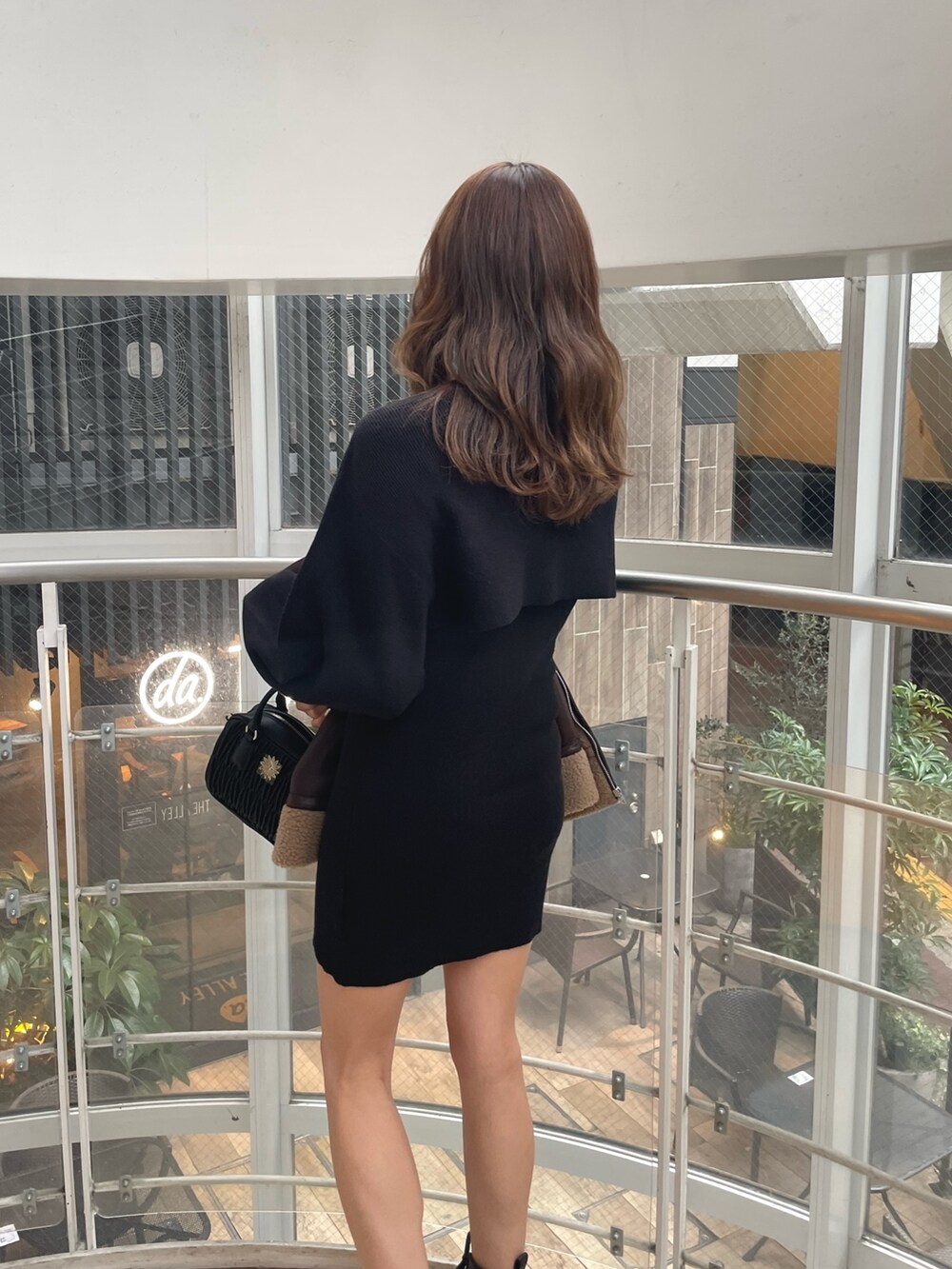 ブラック系のブーツ、ブラック系のショルダーバッグ、ブラウン系のブルゾンを着用したレディースの冬コーディネートの5枚目の写真