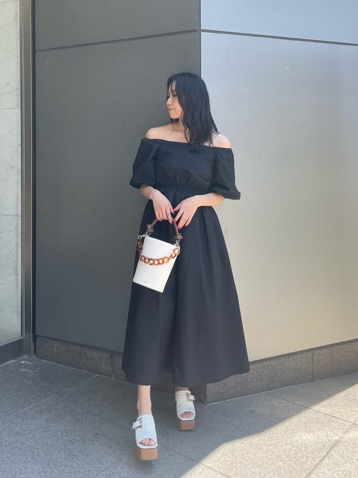 ブラック系のワンピース、ホワイト系のサンダル、ホワイト系のショルダーバッグを着用したレディースの春コーディネートの2枚目の写真