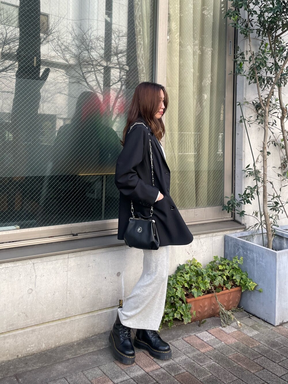 ブラック系のテーラードジャケット、グレー系のワンピース、ブラック系のショルダーバッグを着用したレディースの冬コーディネートの2枚目の写真