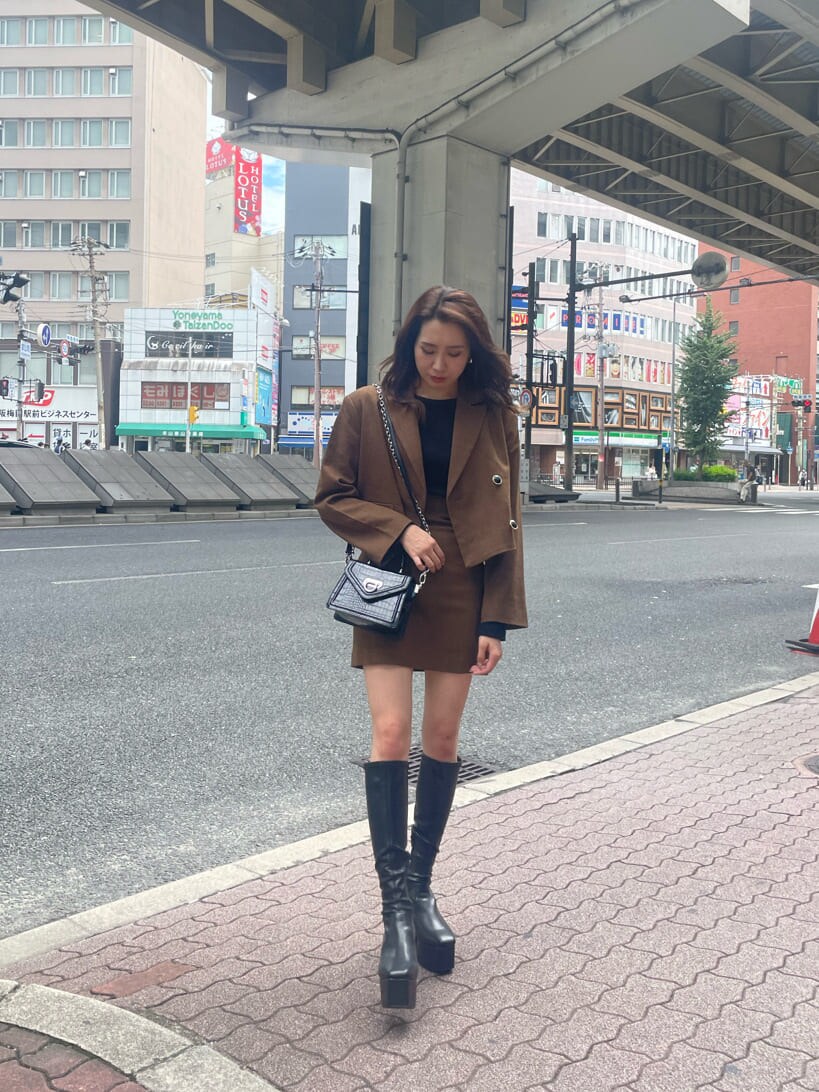 ブラック系のブーツ、ブラック系のTシャツ/カットソー、ブラウン系のテーラードジャケットを着用したレディースの秋コーディネートの2枚目の写真