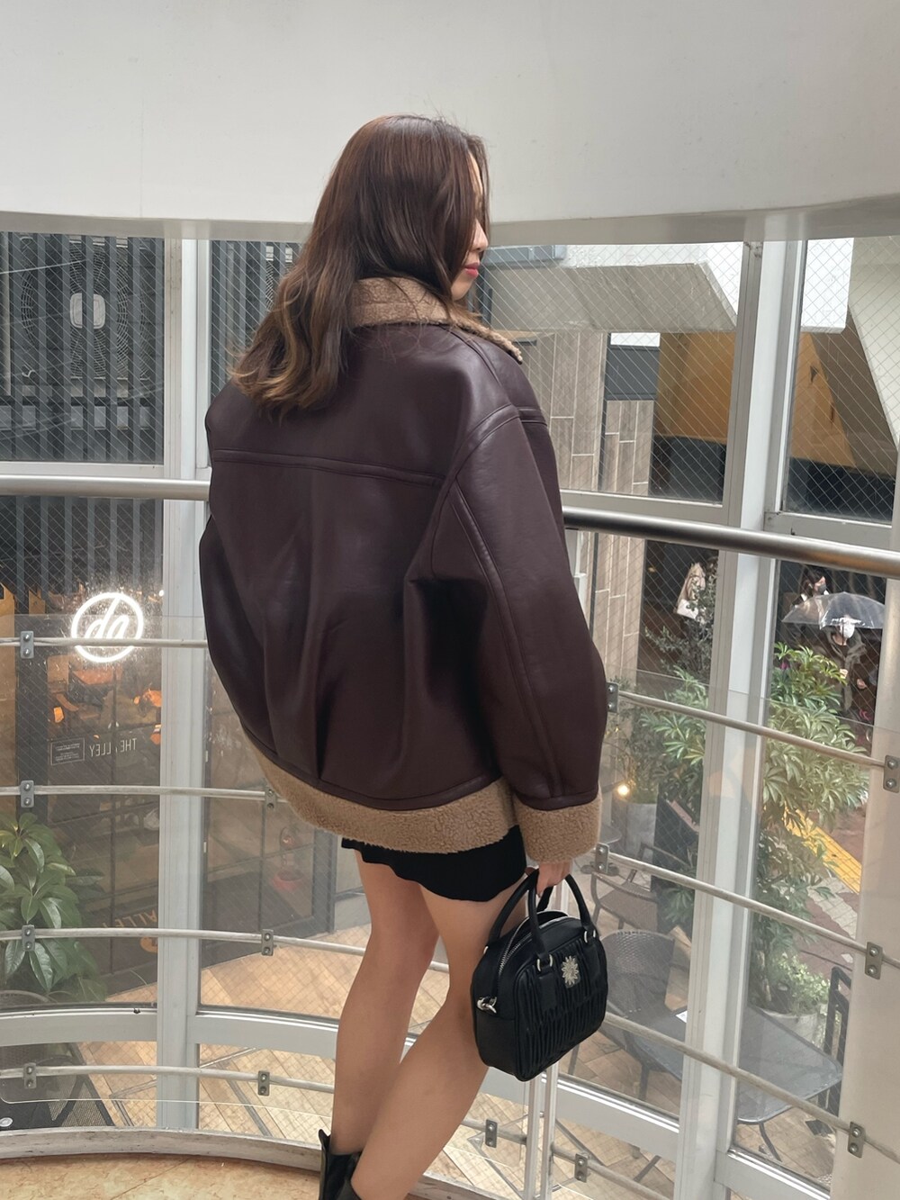 ブラック系のブーツ、ブラック系のショルダーバッグ、ブラウン系のブルゾンを着用したレディースの冬コーディネートの6枚目の写真