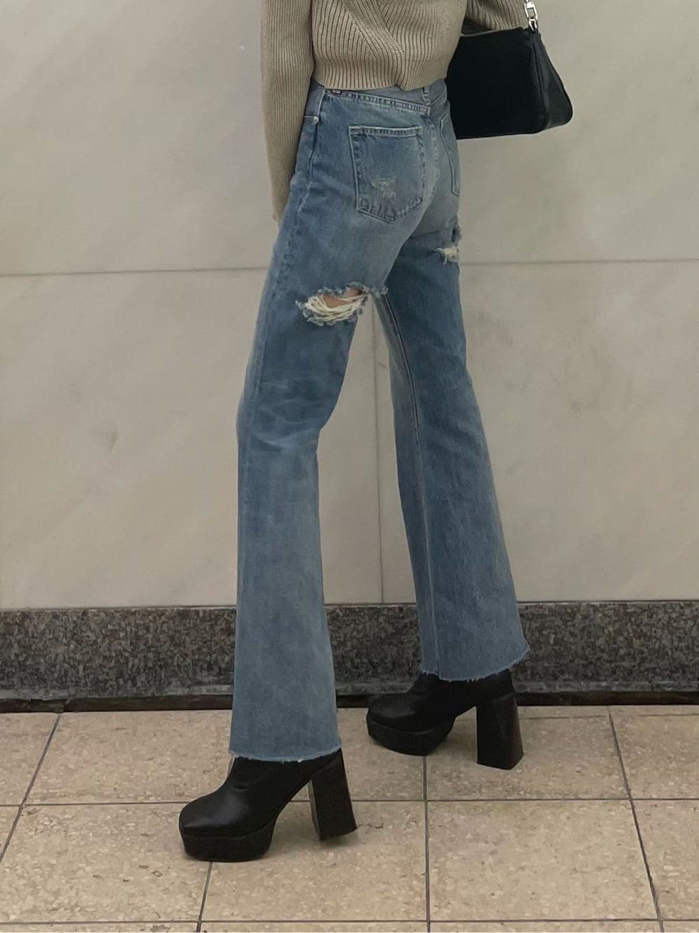 ブルー系のデニムパンツ、ホワイト系のニット/セーター、ブラック系のベルトを着用したレディースの秋コーディネートの3枚目の写真