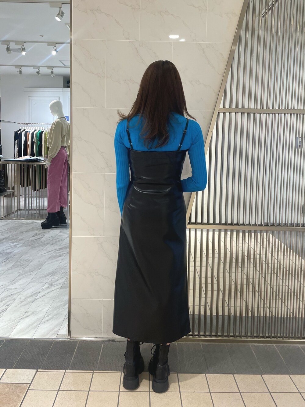 ブルー系のニット/セーター、ブラック系のワンピース、ブラック系のブーツを着用したレディースの春コーディネートの2枚目の写真