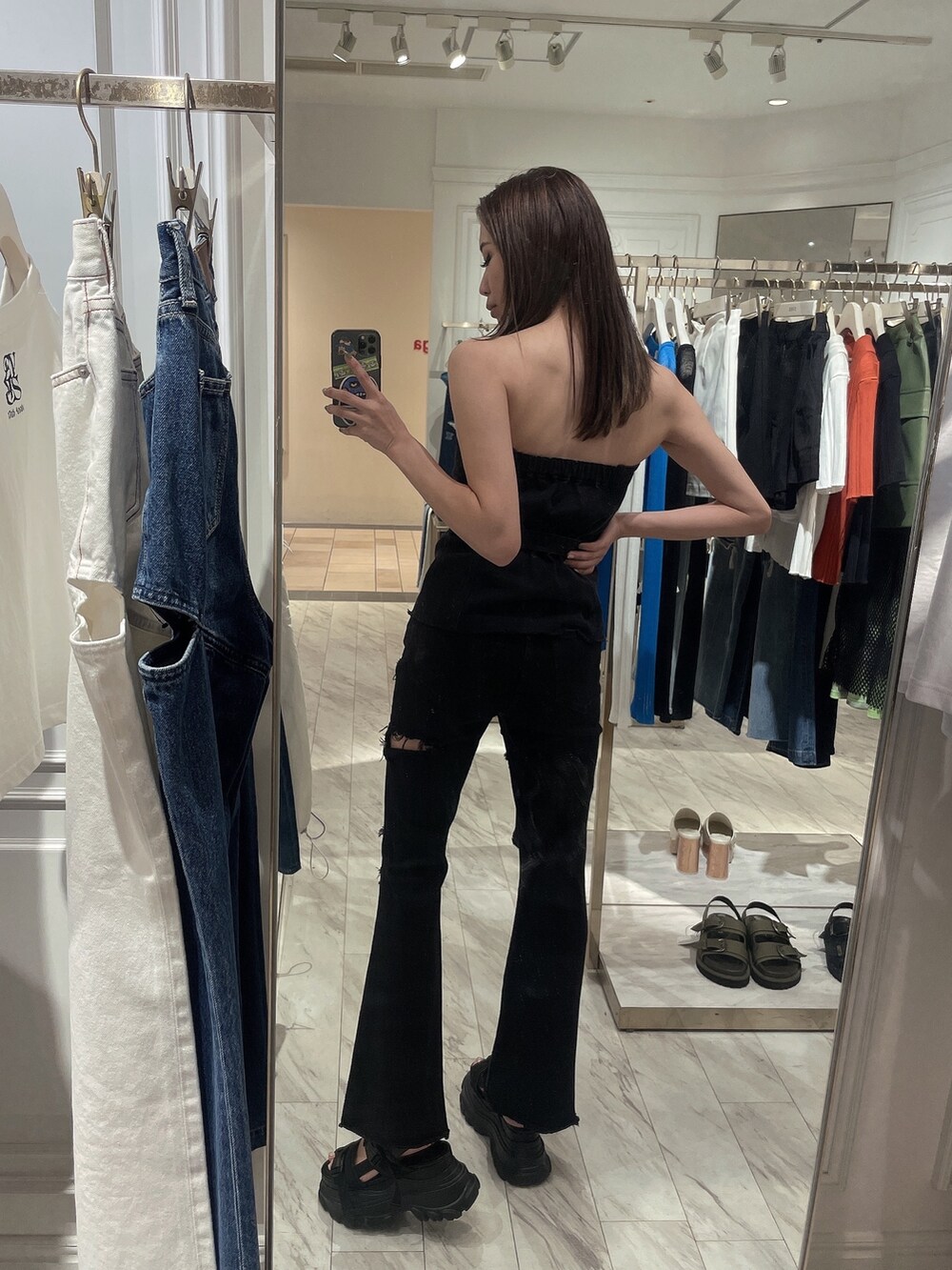 ブラック系のチューブトップ、ブラック系のデニムパンツ、ブラック系のサンダルを着用したレディースの春コーディネートの2枚目の写真