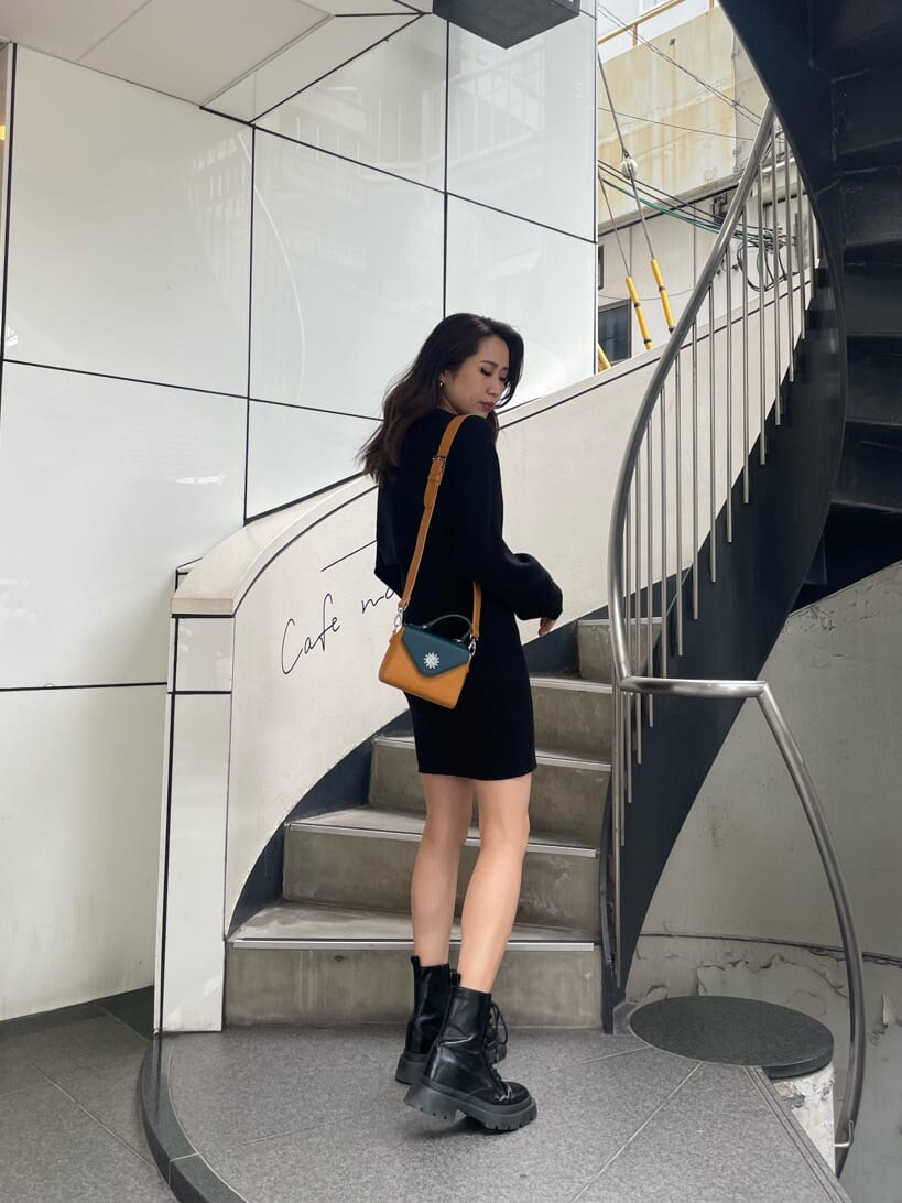 ブラック系のワンピース、ブラック系のブーツ、イエロー系のショルダーバッグを着用したレディースの秋コーディネートの2枚目の写真