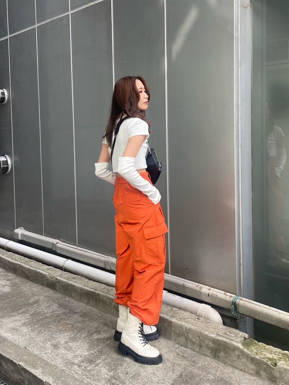 オレンジ系のカーゴパンツ、ホワイト系のTシャツ/カットソー、ホワイト系のブーツを着用したレディースの春コーディネートの3枚目の写真