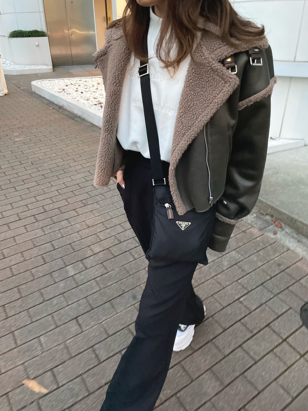 グリーン系のブルゾン、ホワイト系のスウェット、ブラック系のスラックスを着用したレディースの冬コーディネートの3枚目の写真