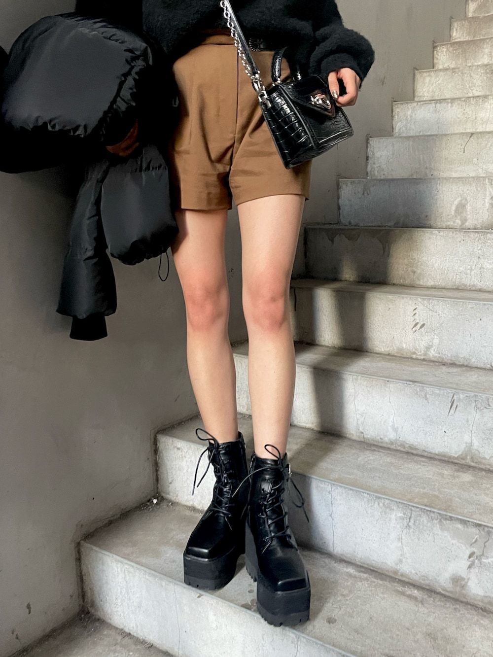 ブラウン系のその他パンツ、ブラック系のハンドバッグ、ブラック系のダウンジャケット/コートを着用したレディースの秋コーディネートの6枚目の写真