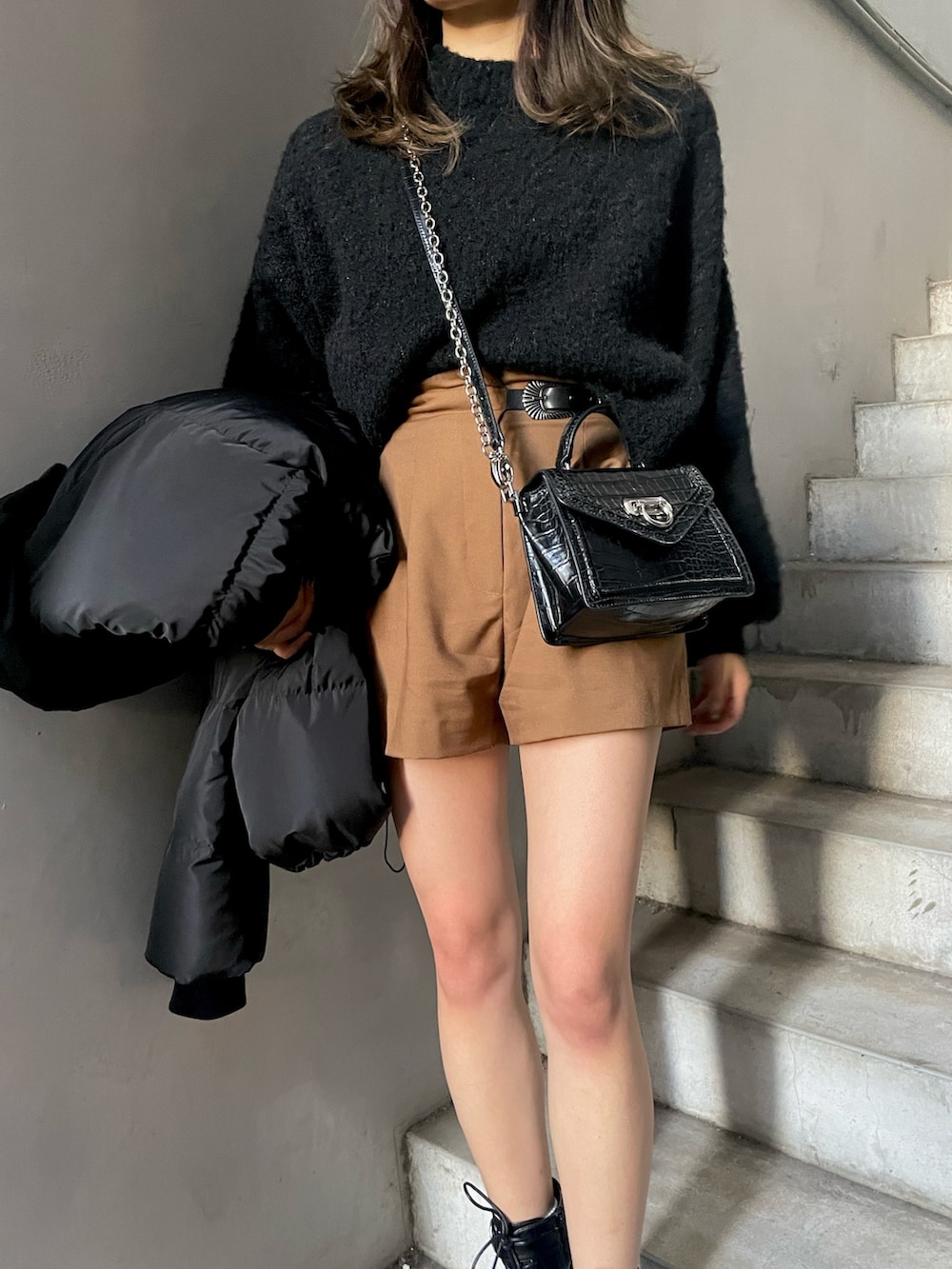 ブラウン系のその他パンツ、ブラック系のハンドバッグ、ブラック系のダウンジャケット/コートを着用したレディースの秋コーディネートの4枚目の写真