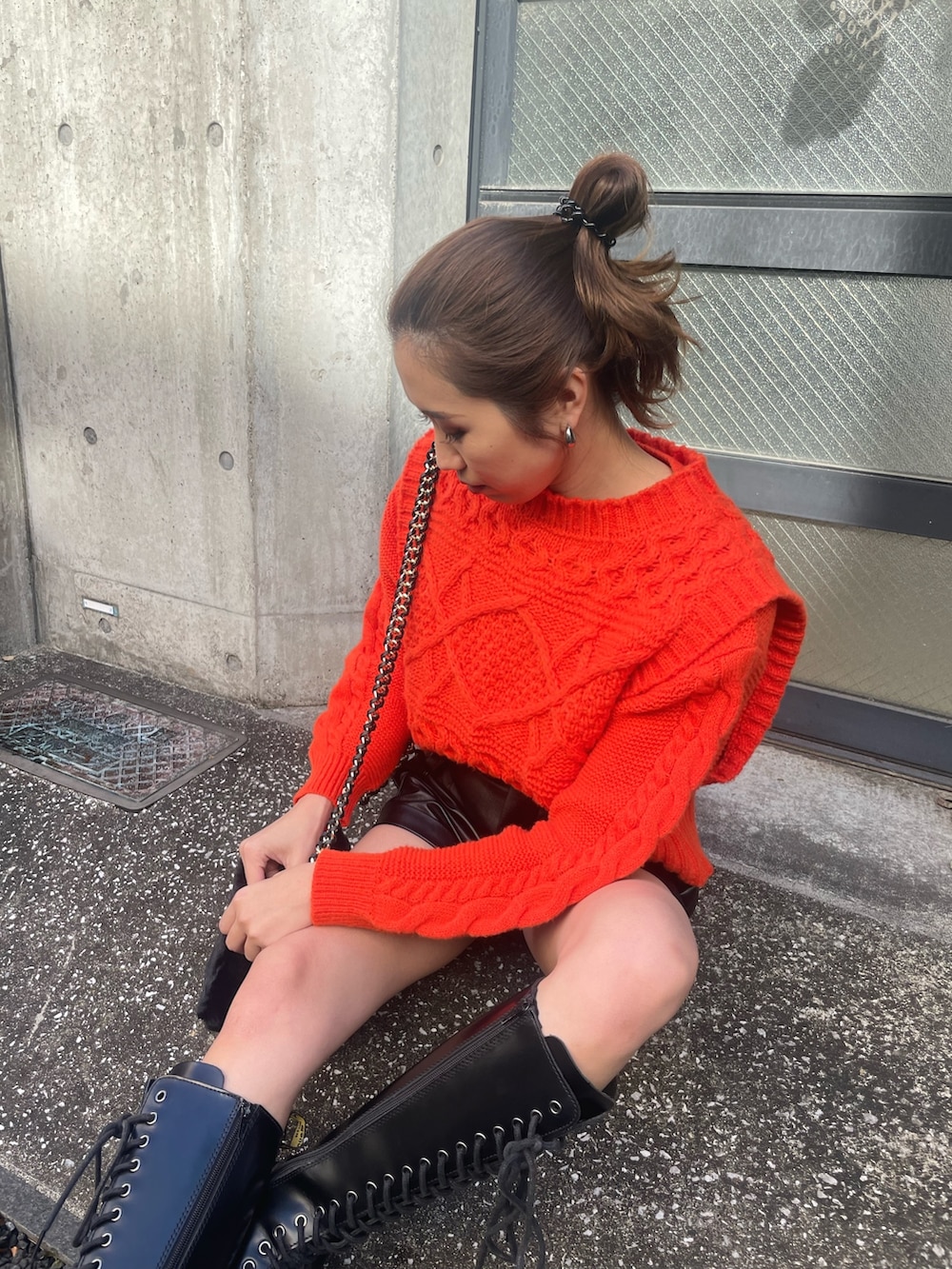 オレンジ系のニット/セーター、ブラック系のその他パンツ、ブラック系のショルダーバッグを着用したレディースの冬コーディネートの2枚目の写真