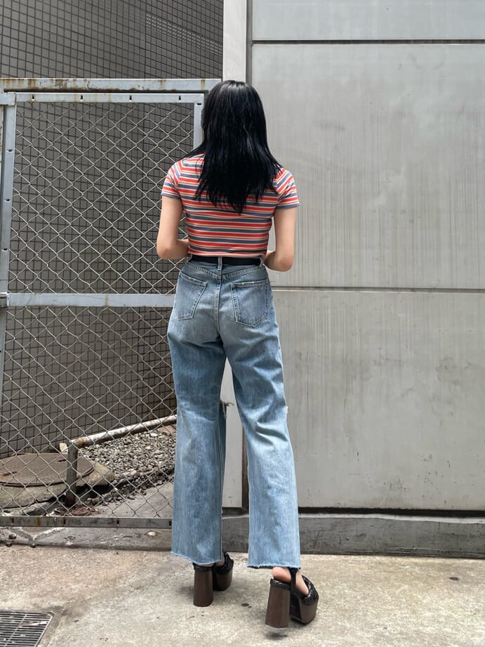 ブラック系のサンダル、ブルー系のデニムパンツ、オレンジ系のTシャツ/カットソーを着用したレディースの夏コーディネートの2枚目の写真