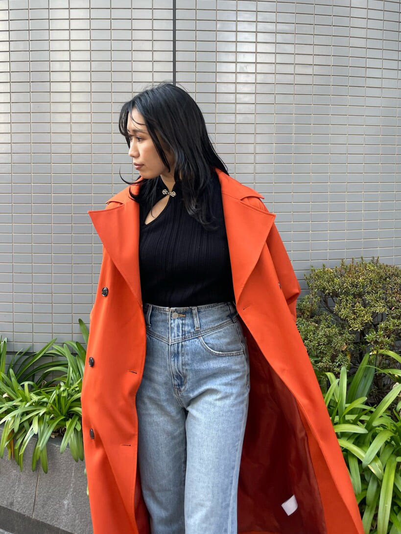 ブラック系のブーツ、オレンジ系のトレンチコート、ブルー系のデニムパンツを着用したレディースの春コーディネートの7枚目の写真