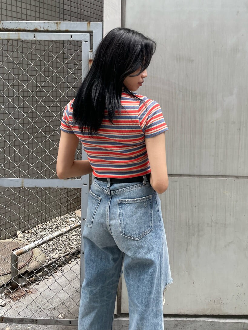 ブラック系のサンダル、ブルー系のデニムパンツ、オレンジ系のTシャツ/カットソーを着用したレディースの夏コーディネートの4枚目の写真